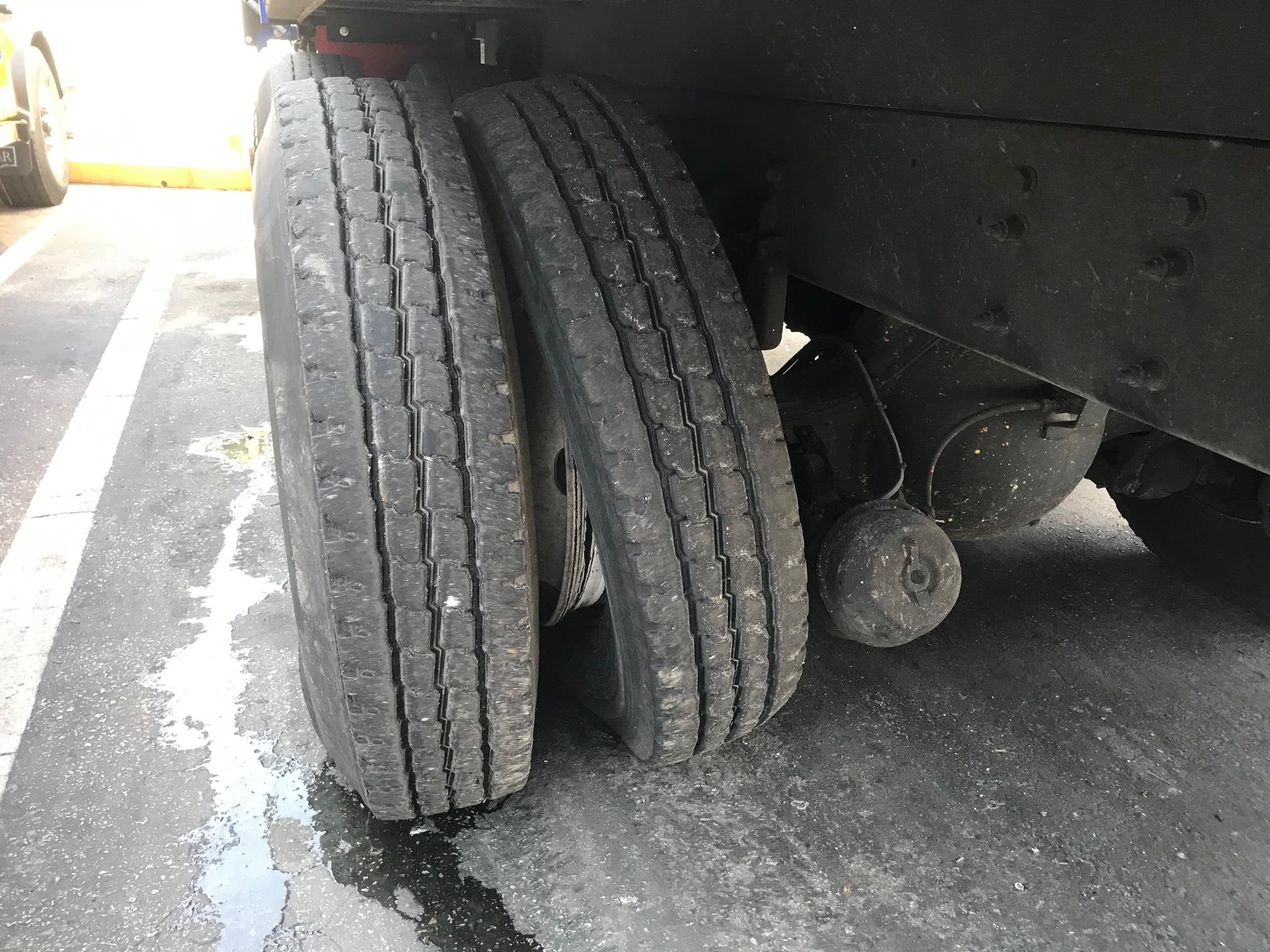 Semi-truck dual rear wheels close-up on pavement.