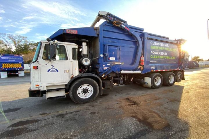 Natural gas-powered garbage truck in sunlight.