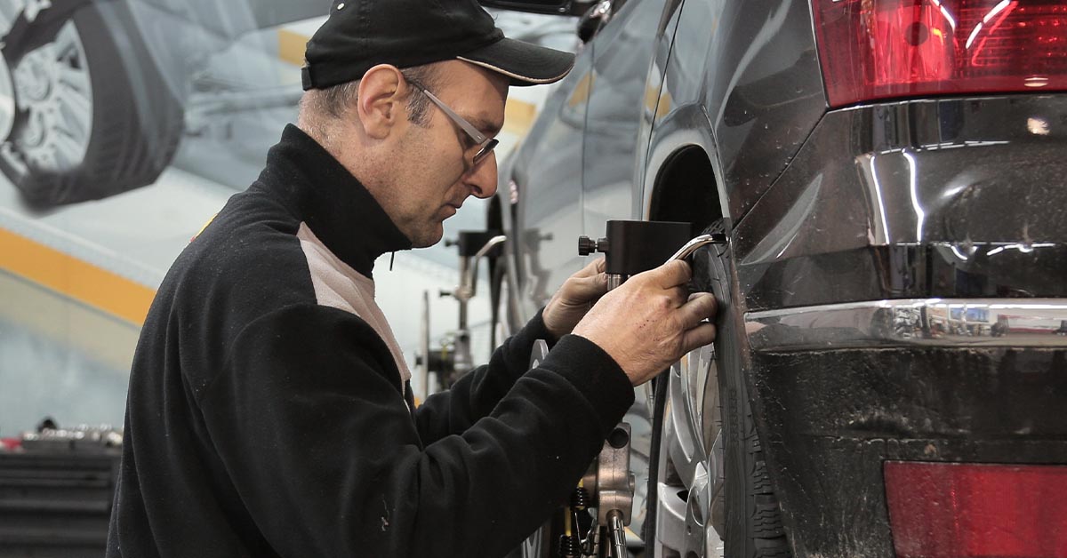 Mechanic adjusting car wheel alignment.