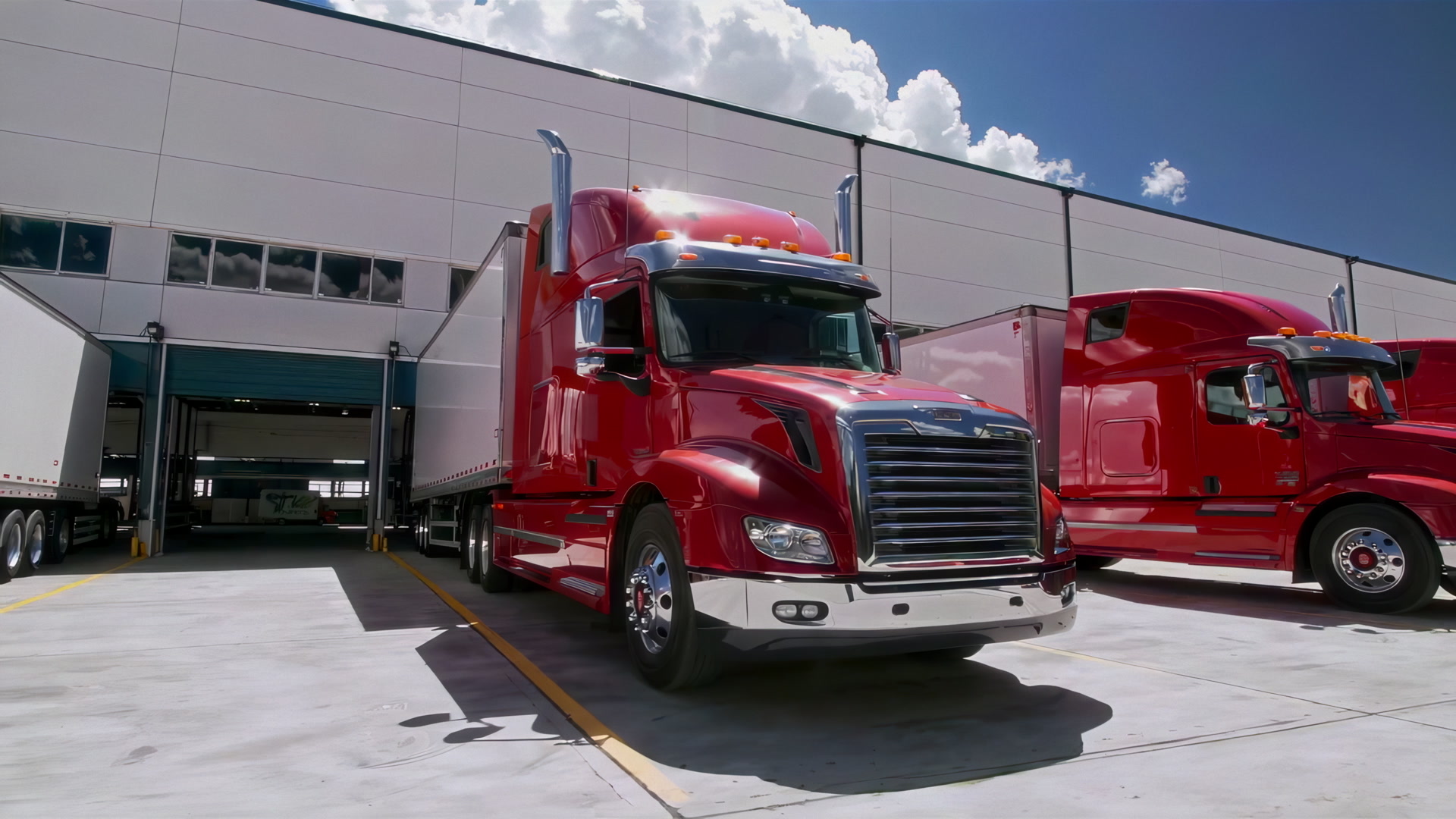 Red semi-trucks parked at a large distribution center